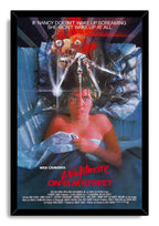 A Nightmare on Elm Street framed wall art print depicts Nancy clutching blue sheets beneath a sinister clawed figure.
