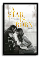 A Star Is Born framed wall art print in a black border, with gold title text and a grayscale couple beside a guitar.