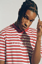 A$AP Rocky poster portrait in a red and white striped Guess Jeans shirt, holding a braid against a pale background.