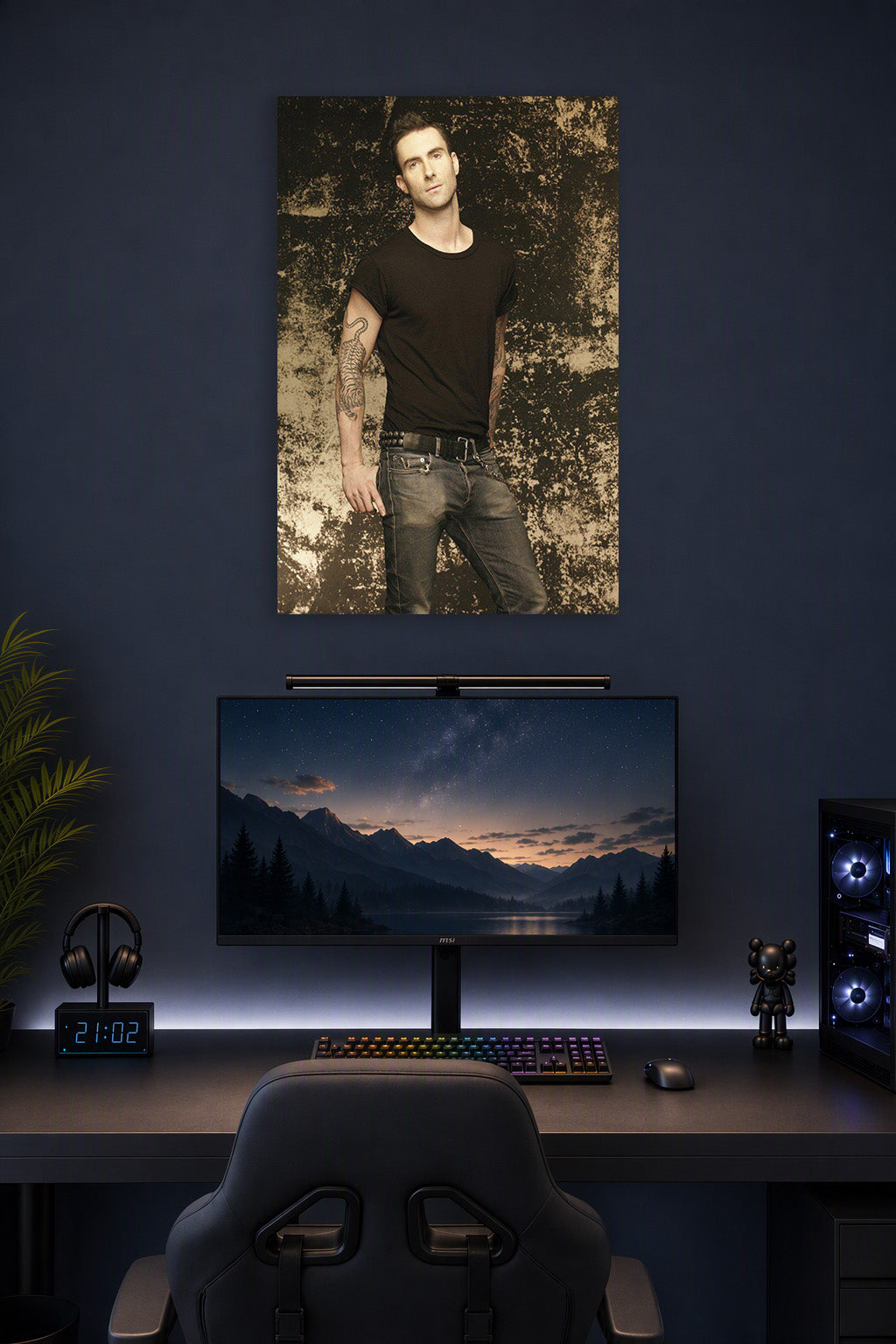 Adam Levine in a gaming desk setup above a monitor.