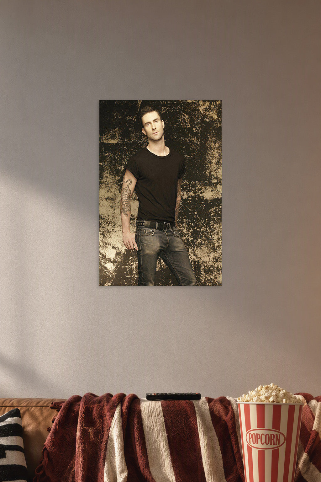Adam Levine in a cozy movie room above a brown sofa with popcorn.