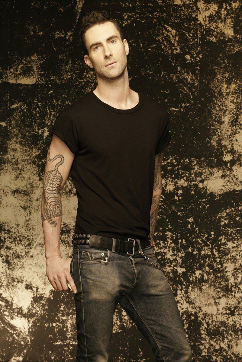 Adam Levine wall art print portrays the singer in a black T-shirt and jeans before a distressed black and tan backdrop.
