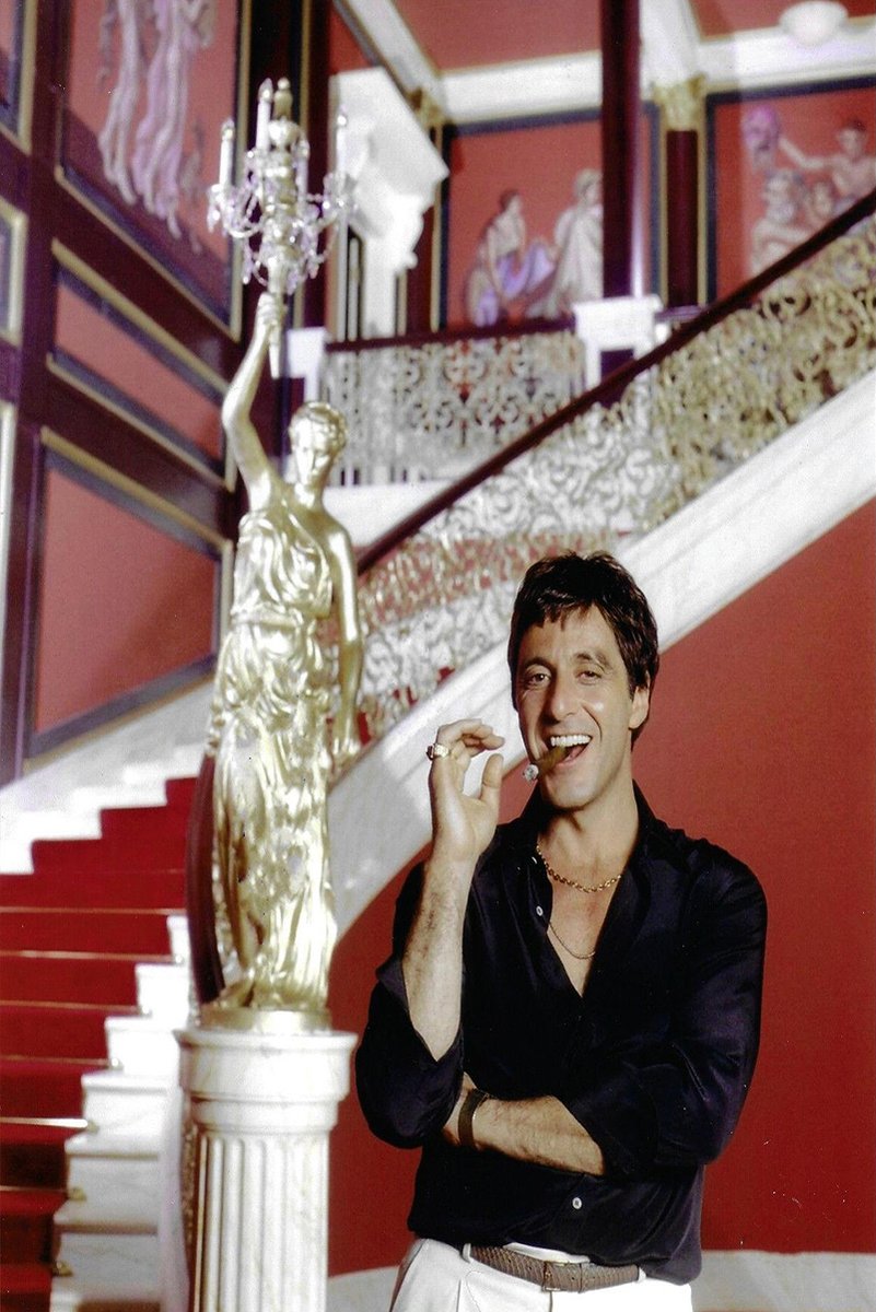 Tony Montana poster features Al Pacino smiling with a cigar beside a gilded statue and red mansion staircase.