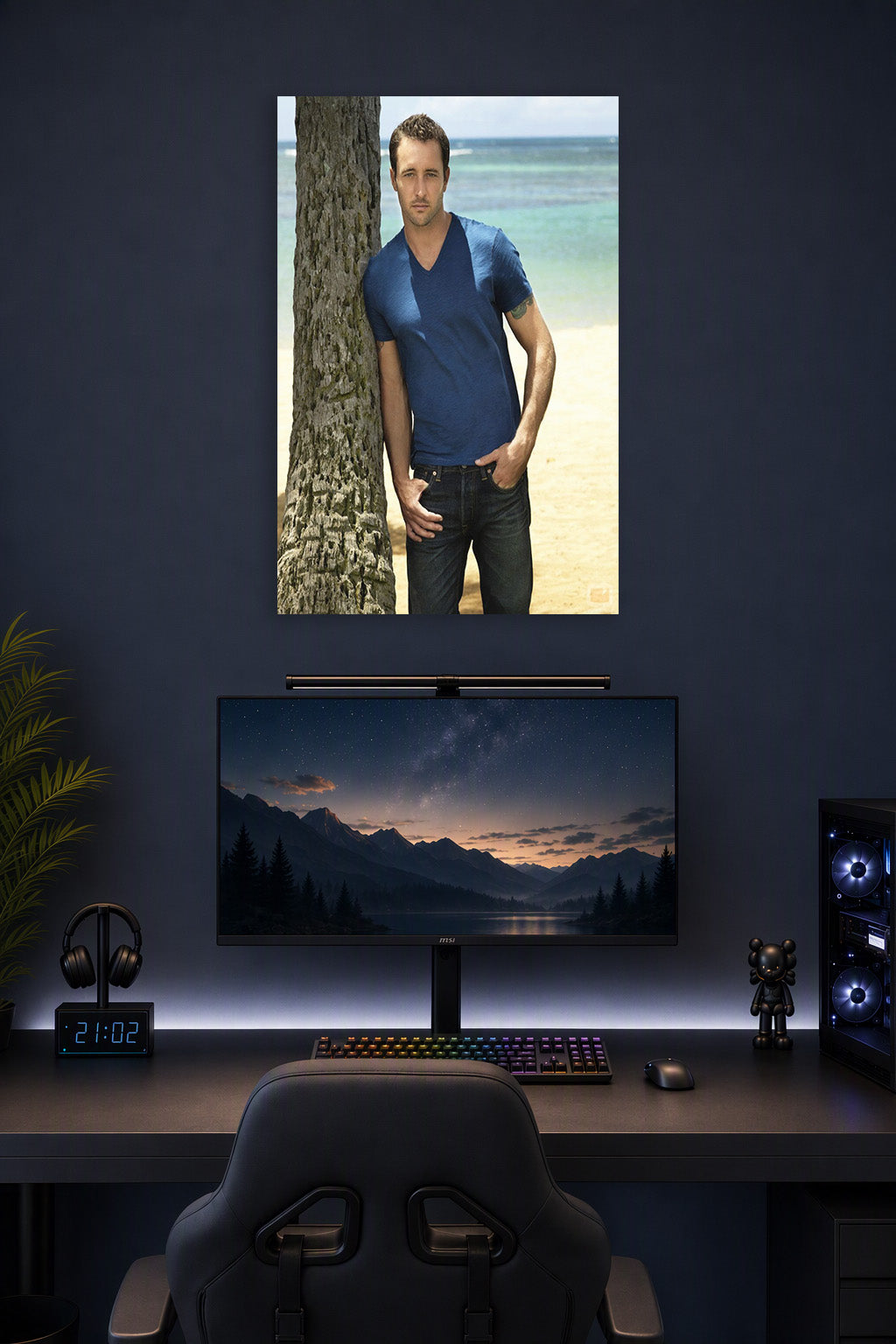 Alex O'Loughlin in a gaming desk setup above a monitor.