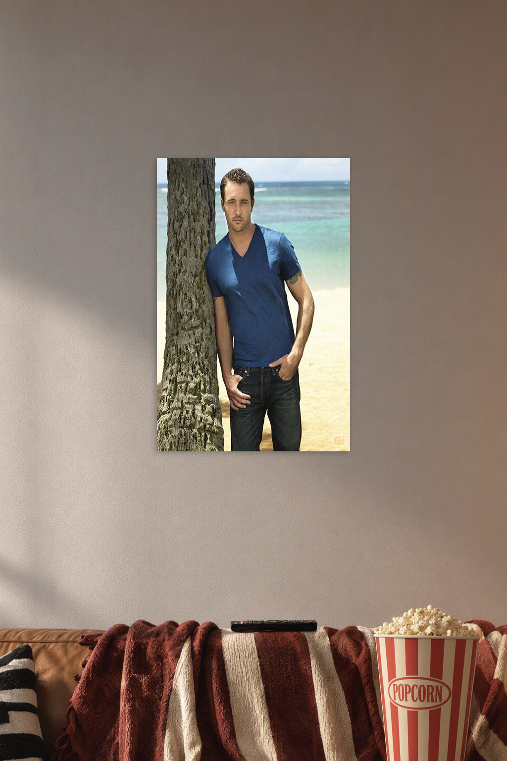 Alex O'Loughlin in a cozy movie room above a brown sofa with popcorn.
