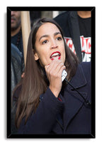 Alexandria Ocasio-Cortez framed wall art print depicts her addressing a crowd with a white microphone, set in a black frame.