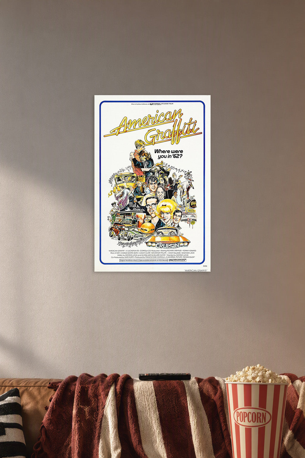 American Graffiti Movie Poster in a cozy movie room above a brown sofa with popcorn.