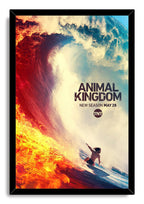 Animal Kingdom framed wall art print depicts a lone surfer riding blue water beside a towering wave streaked with blazing orange fire.
