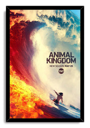 Animal Kingdom framed wall art print depicts a lone surfer riding blue water beside a towering wave streaked with blazing orange fire.