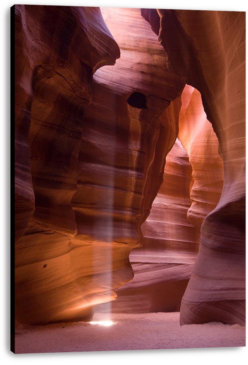 Antelope Canyon canvas wall art print with warm layered sandstone passage and a bright beam reaching the sandy floor.