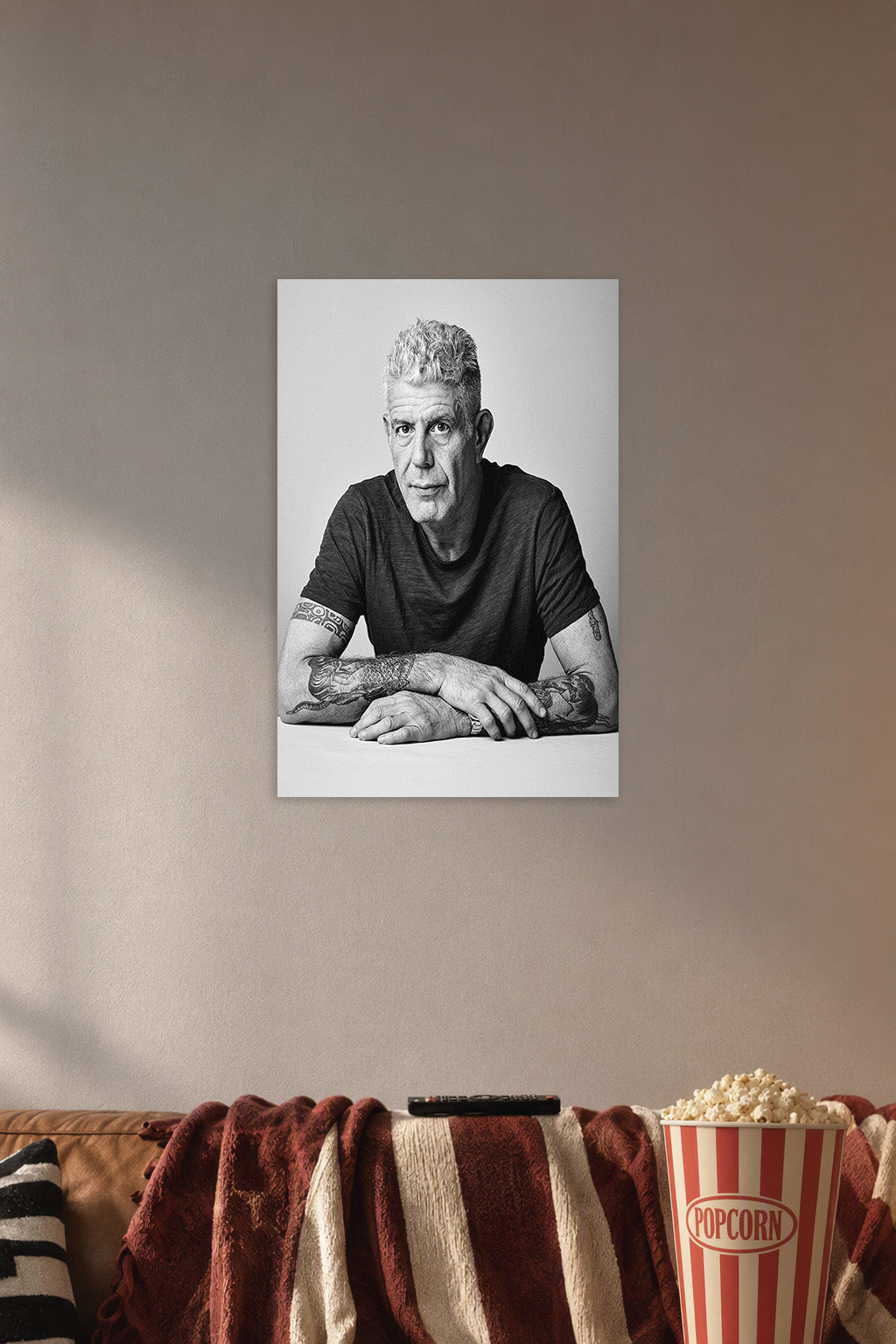 Anthony Bourdain in a cozy movie room above a brown sofa with popcorn.