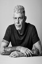Anthony Bourdain wall art print features a black-and-white portrait of the tattooed chef seated with folded arms.