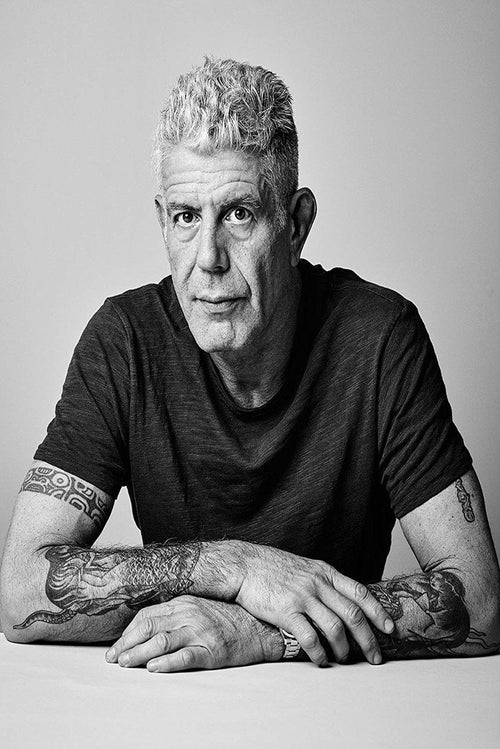 Anthony Bourdain wall art print features a black-and-white portrait of the tattooed chef seated with folded arms.