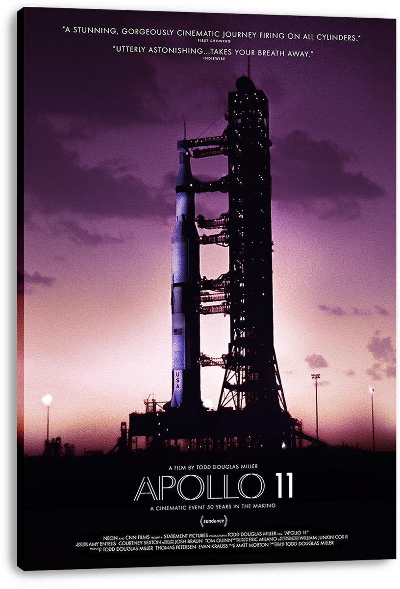 Apollo 11 canvas wall art print displays a Saturn V rocket beside its dark launch gantry beneath a purple sunset sky.