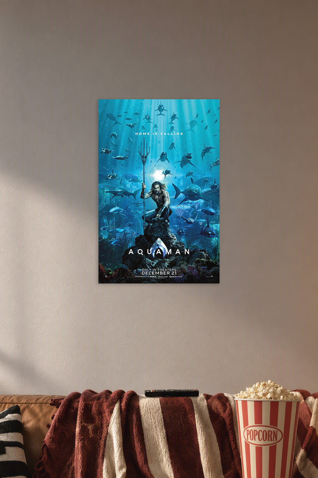 Aquaman Movie Poster in a cozy movie room above a brown sofa with popcorn.