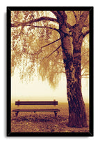 Autumn park bench wall art print in a black frame, with a towering tree and sepia leaves in soft morning mist.