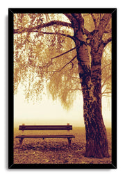 Autumn park bench wall art print in a black frame, with a towering tree and sepia leaves in soft morning mist.