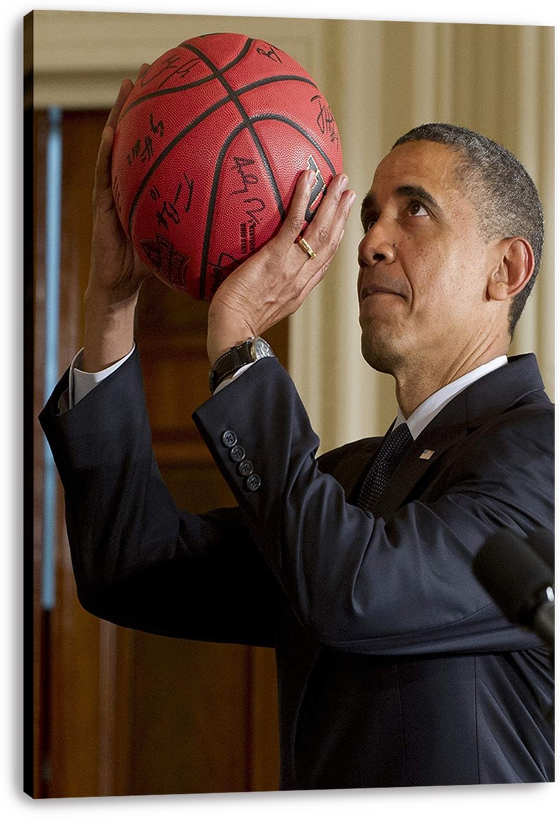 Barack Obama canvas wall art print portrays him in a navy suit holding a red autographed basketball overhead.
