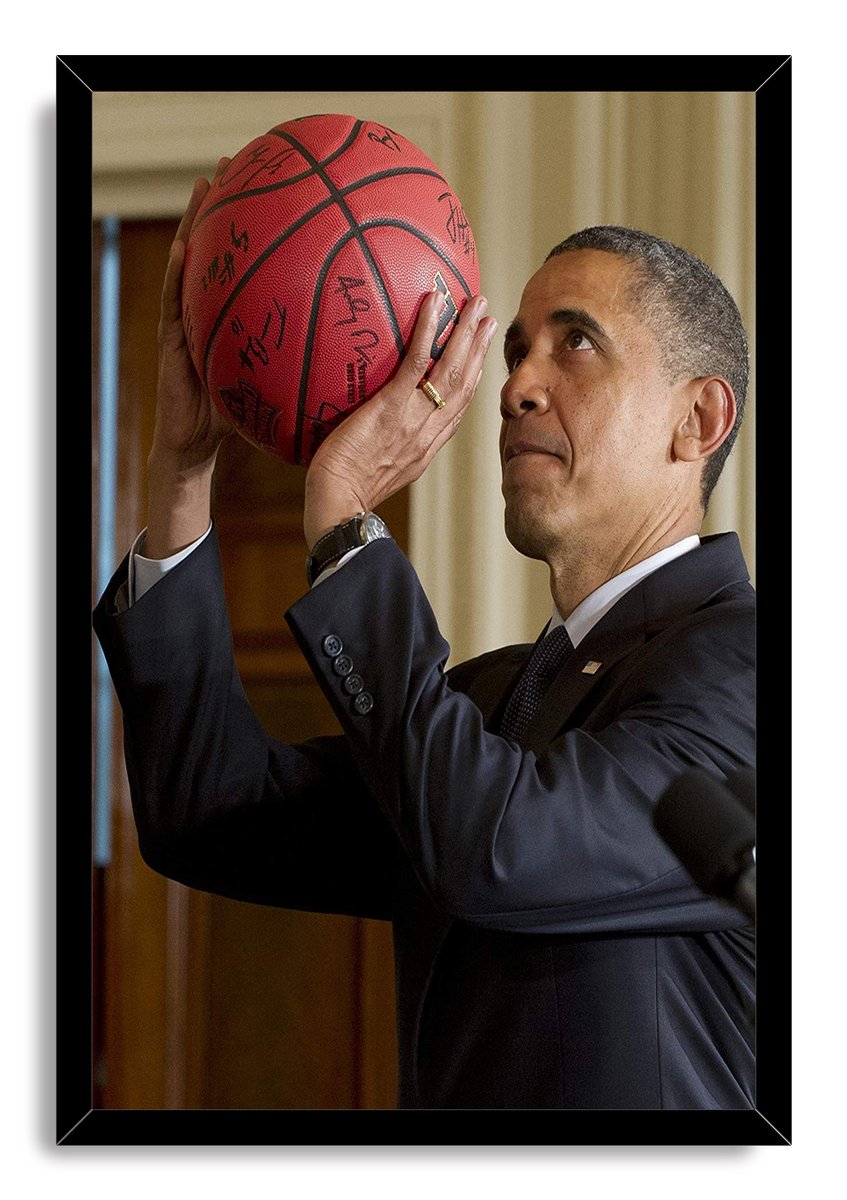 Barack Obama framed wall art print depicts him gazing at a red signed basketball, set in a black frame.