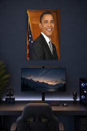 Barack Obama in a gaming desk setup above a monitor.