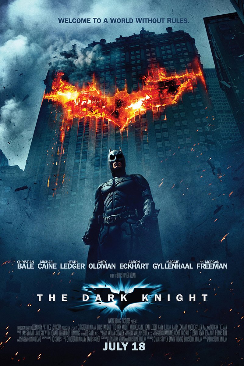 Batman The Dark Knight poster depicts Batman before a skyscraper bearing a fiery bat symbol amid blue-gray smoke.