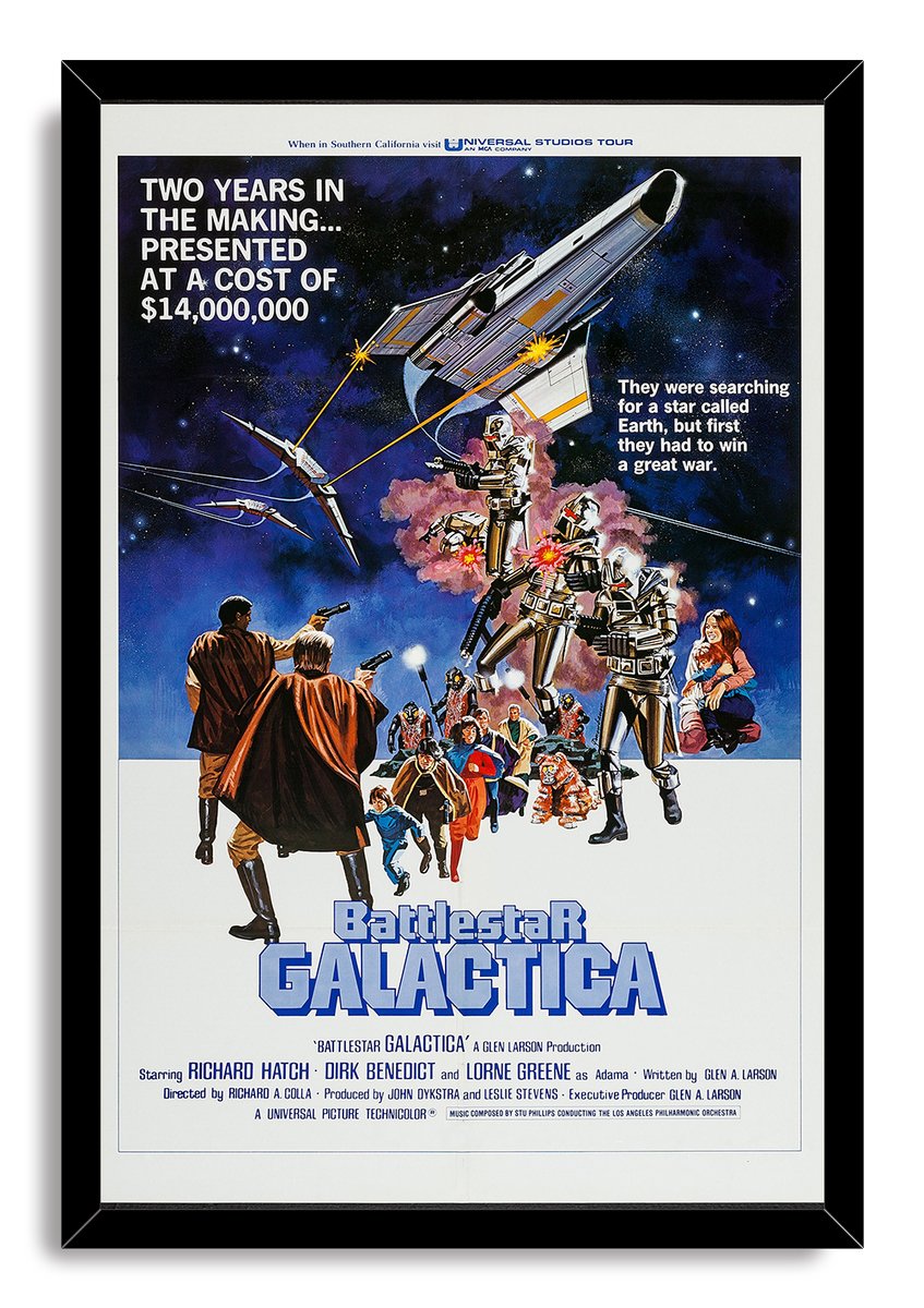 Battlestar Galactica framed wall art print displays silver robots under a spacecraft, armed heroes, and blue science-fiction title lettering.