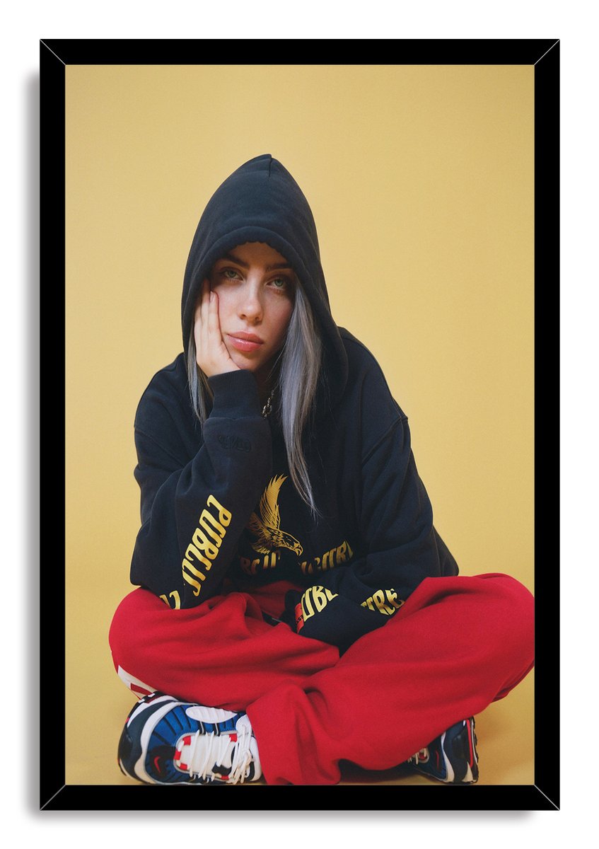 Billie Eilish framed wall art print depicts the singer resting her face on one hand against a warm yellow background.