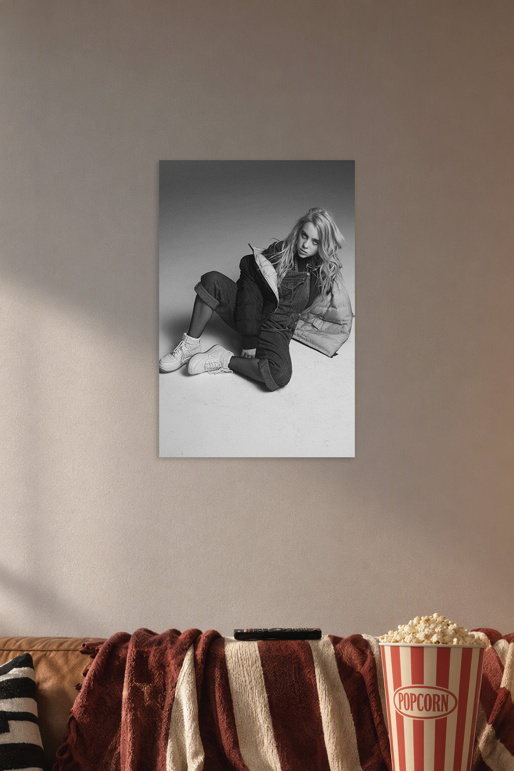 Billie Eilish in a cozy movie room above a brown sofa with popcorn.