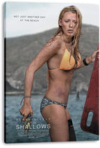 The Shallows canvas wall art print displays Blake Lively beside a red surfboard, with ocean water and a shark fin behind her.
