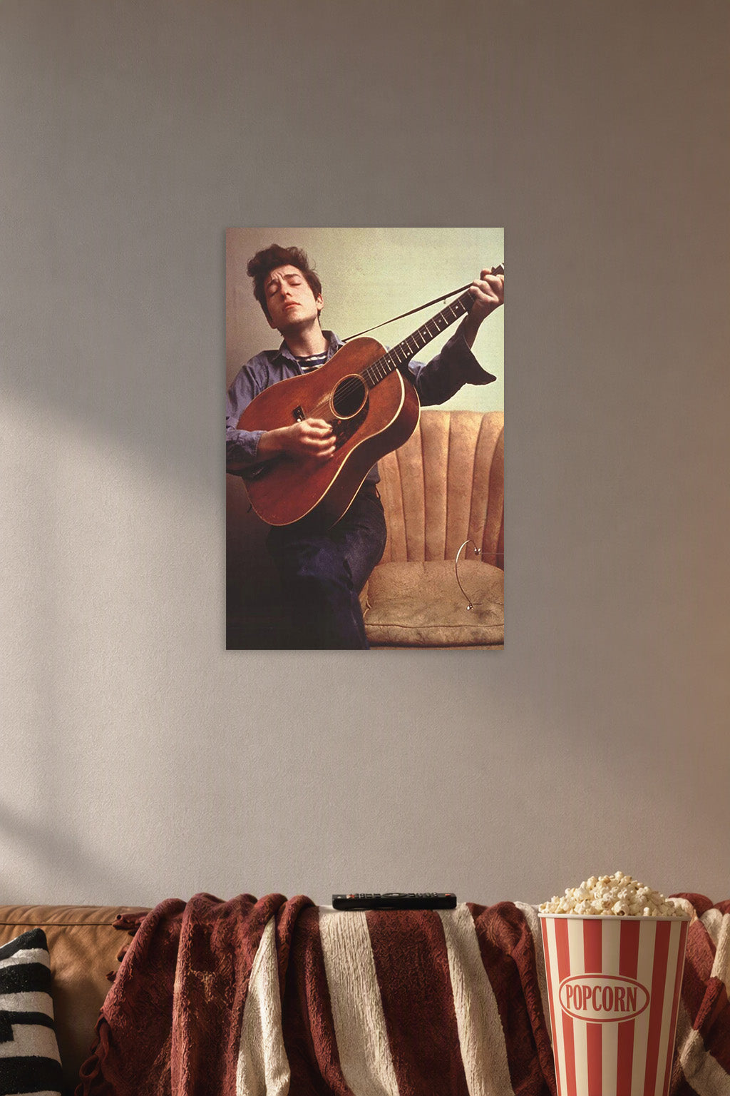 Bob Dylan in a cozy movie room above a brown sofa with popcorn.