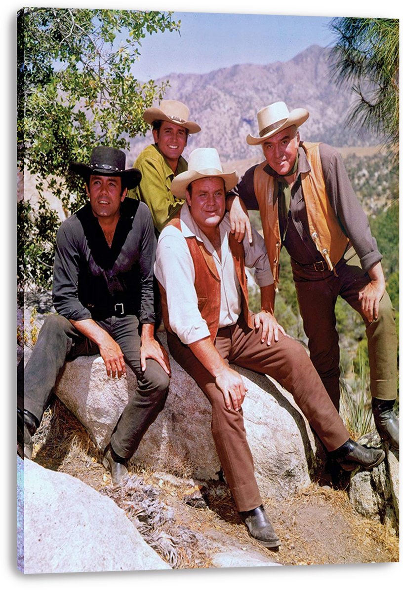Bonanza canvas wall art print features four Western-dressed men in cowboy hats seated and standing on rocks before mountain scenery.