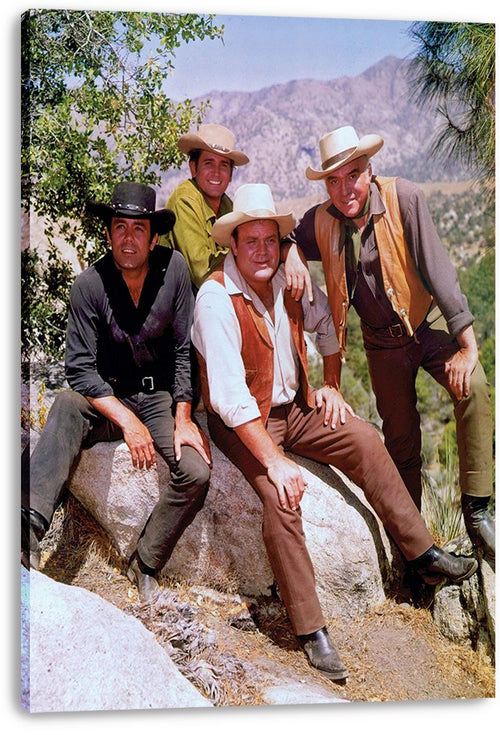 Bonanza canvas wall art print features four Western-dressed men in cowboy hats seated and standing on rocks before mountain scenery.