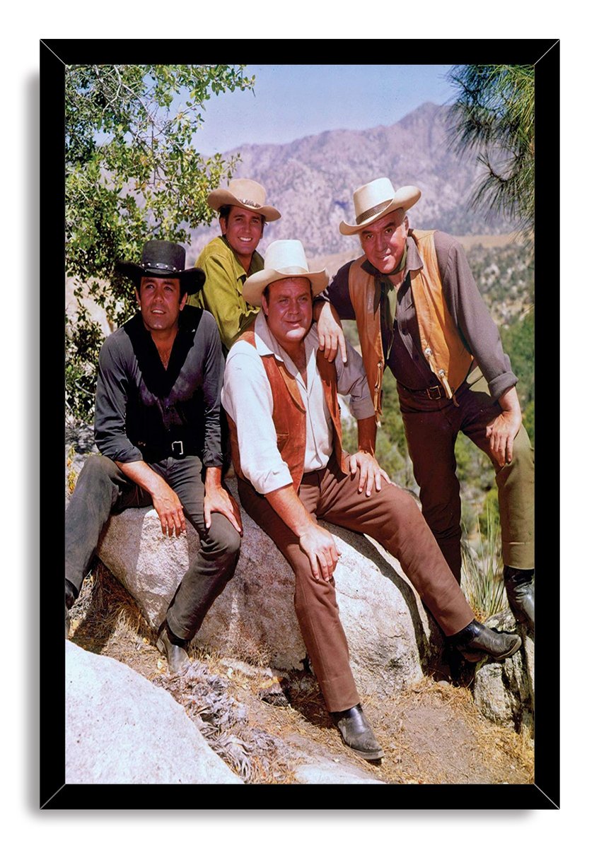 Framed Bonanza wall art print portrays four cowboy-hatted men posed on sunlit boulders, with trees and rugged mountains behind them.