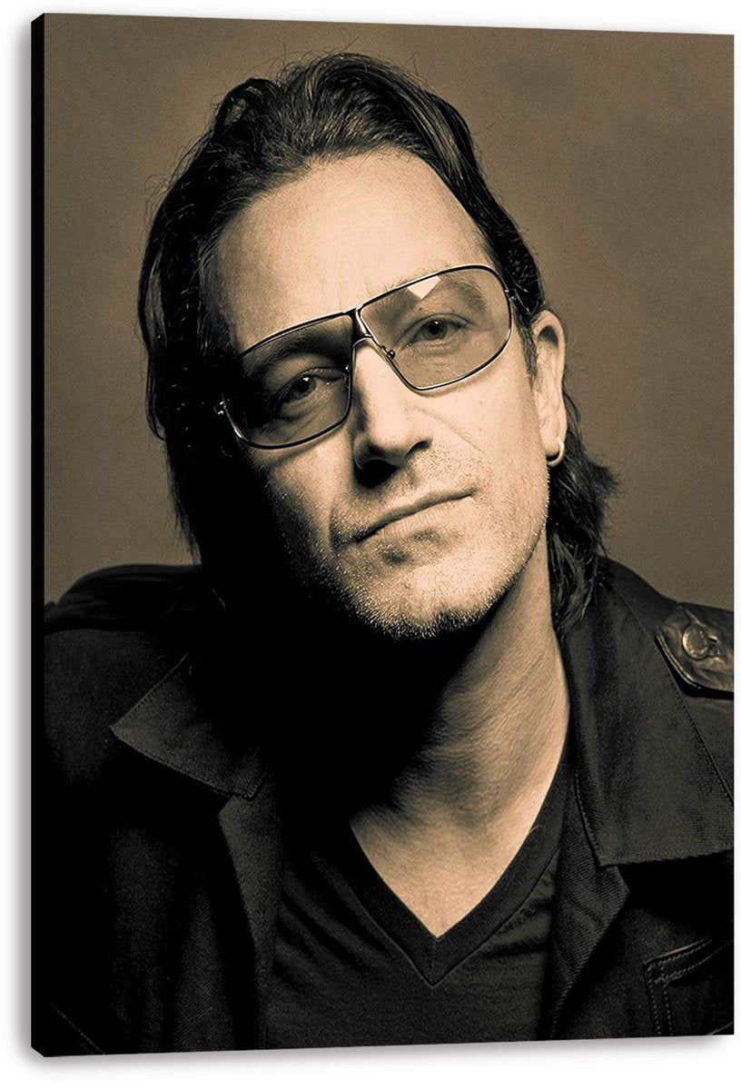 Bono canvas wall art print presents a sepia close-up portrait with tinted aviator glasses, dark layered clothing, and visible wrapped edges.