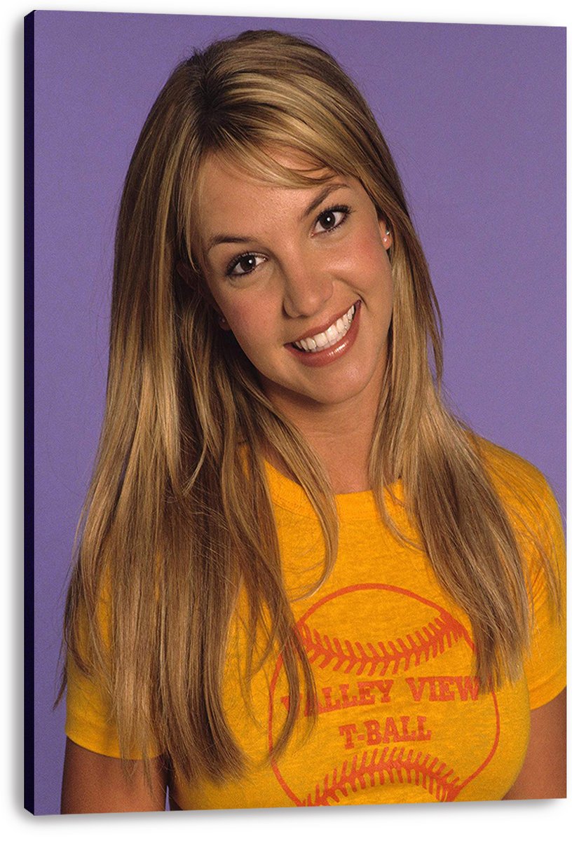 Britney Spears canvas wall art print featuring her smiling portrait in a yellow baseball graphic T-shirt on purple.