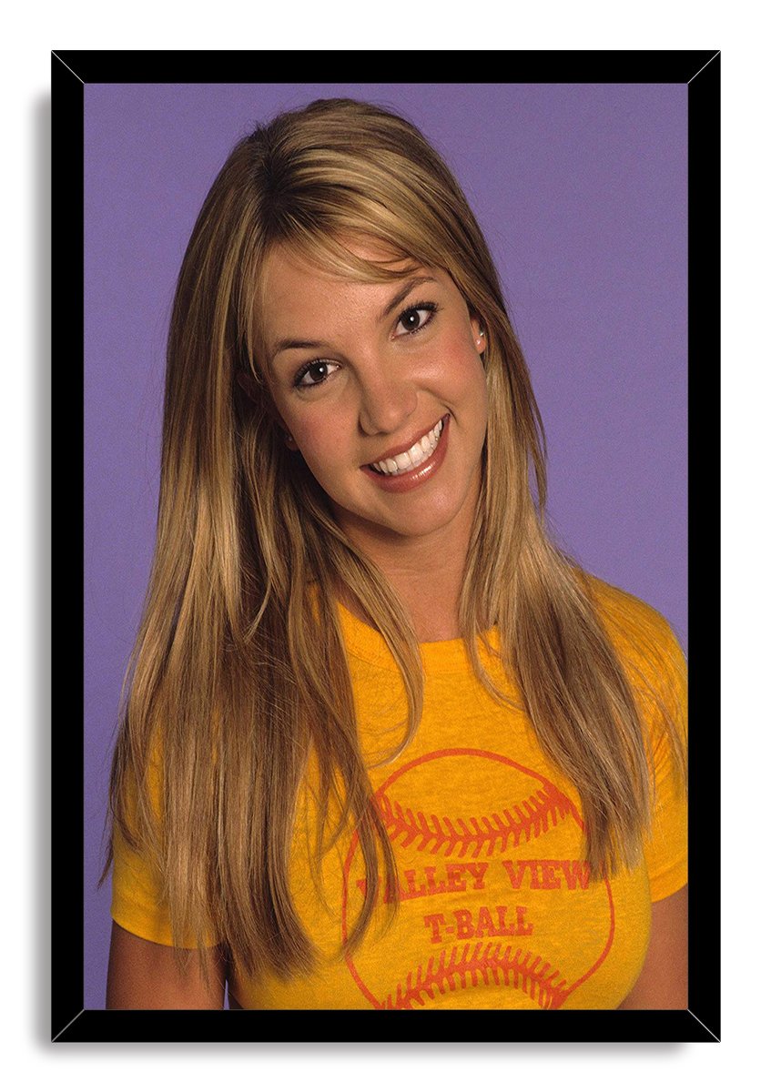 Britney Spears framed wall art print with a black border, portraying her smiling in a yellow T-shirt against purple.