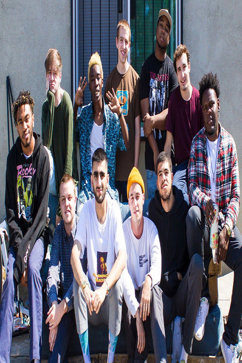 Brockhampton wall art print featuring eleven members gathered outdoors in casual colorful clothing before a gray building.