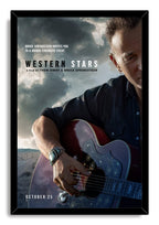 Bruce Springsteen Western Stars wall art print in a black frame portrays him playing a decorated guitar under dramatic clouds.