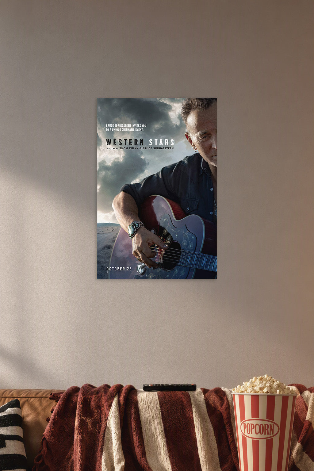 Bruce Springsteen in a cozy movie room above a brown sofa with popcorn.