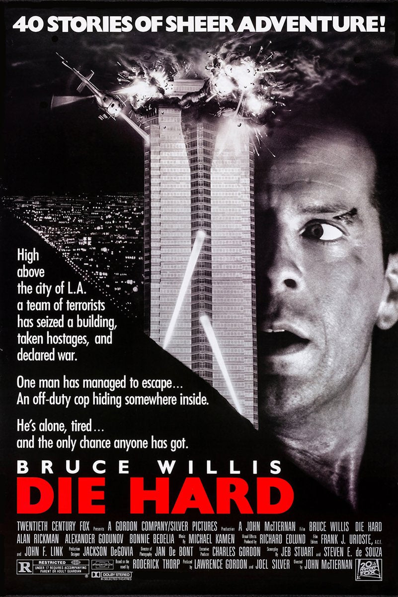 Die Hard movie poster wall art with Bruce Willis beside an exploding skyscraper, helicopter, city lights, and red title text.