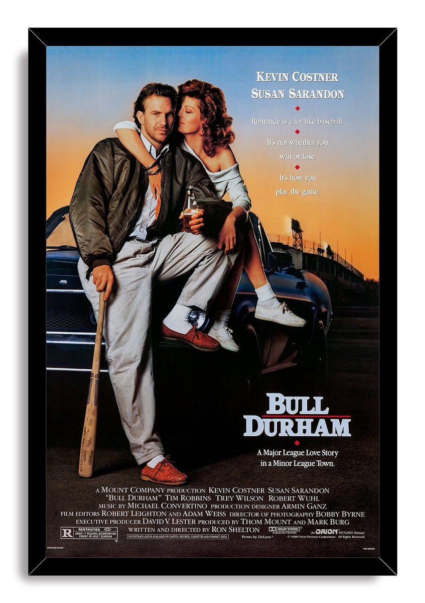 Bull Durham framed wall art print portrays Kevin Costner and Susan Sarandon on a car, with a baseball bat and black frame.