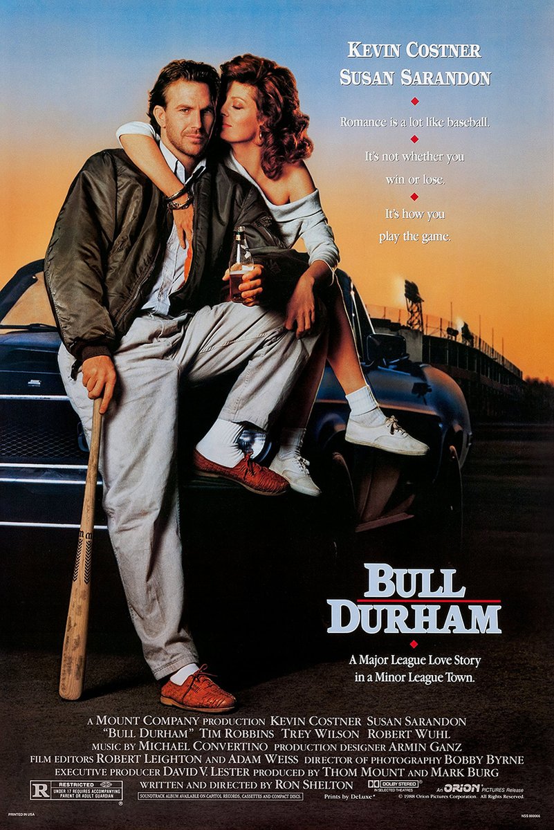 Bull Durham movie poster features Kevin Costner seated with Susan Sarandon on a car, holding a bat at sunset.
