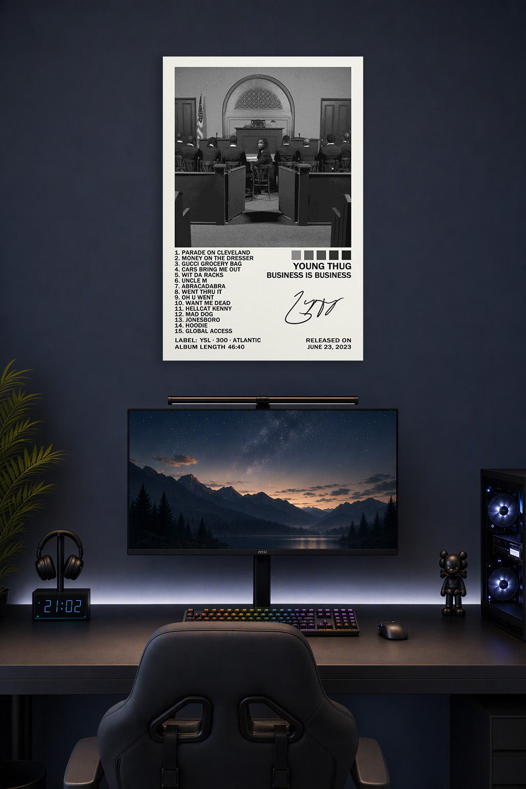 Business Is Business Poster in a gaming desk setup above a monitor.