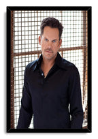 Male celebrity framed wall art print with a blue-eyed man in a black shirt before a sunlit square-grid backdrop.