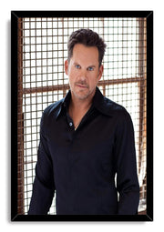 Male celebrity framed wall art print with a blue-eyed man in a black shirt before a sunlit square-grid backdrop.