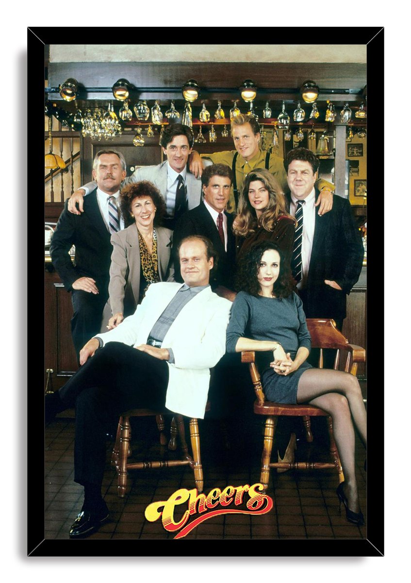 Cheers framed wall art print featuring the ensemble in a classic bar interior, set in a slim black frame with the logo below.