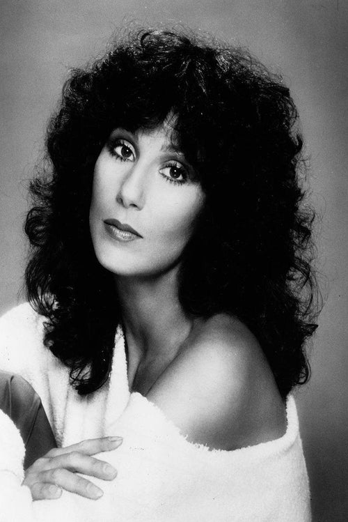 Cher wall art print features a black-and-white studio portrait with voluminous dark curls, a white off-shoulder wrap, and a direct gaze.