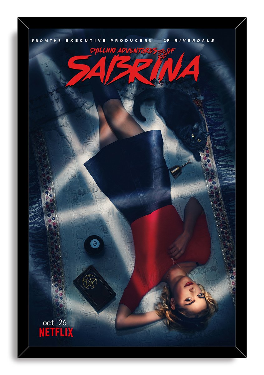 Chilling Adventures of Sabrina framed wall art print of Sabrina reclining beside a black cat, 8-ball, and pentagram-marked book.