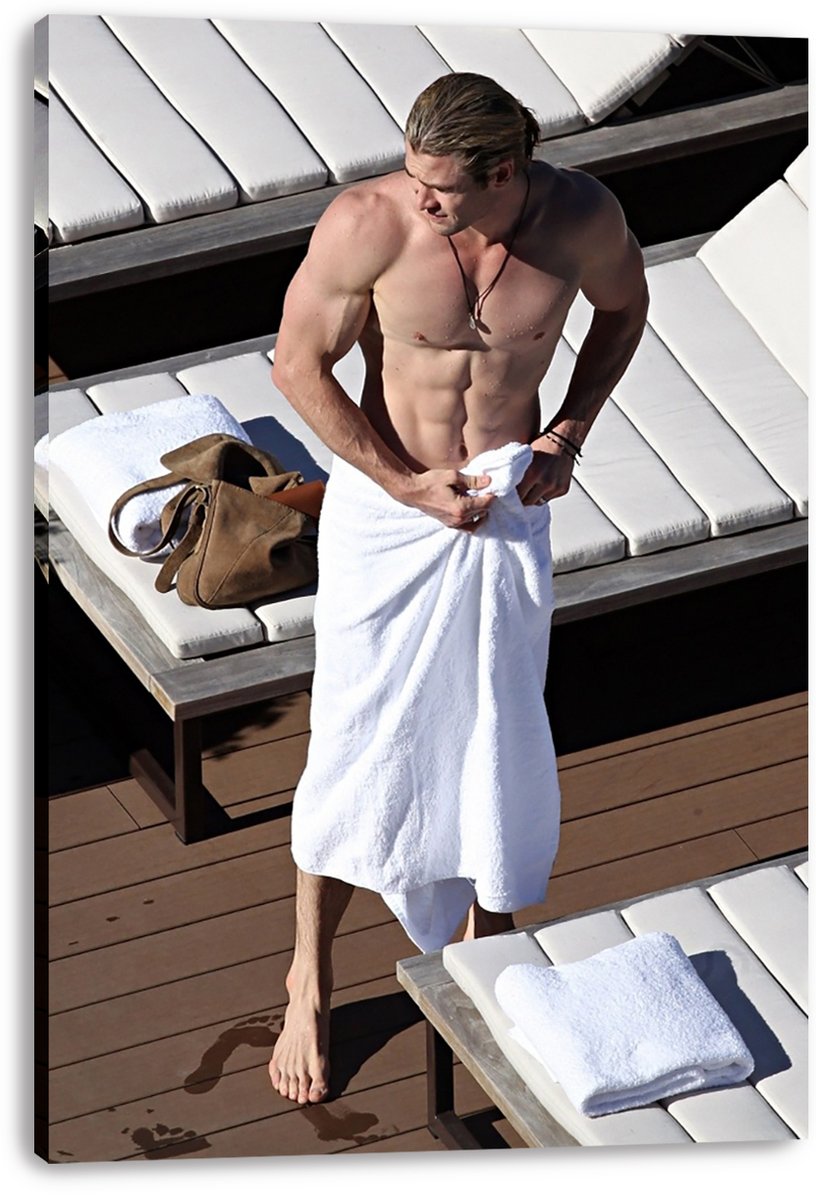 Chris Hemsworth canvas wall art print displays the shirtless actor in a white towel near loungers, folded towels, and a brown bag.