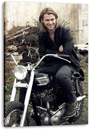 Chris Hemsworth canvas wall art print displays the smiling actor on a black motorcycle, with wrapped edges visible against white.